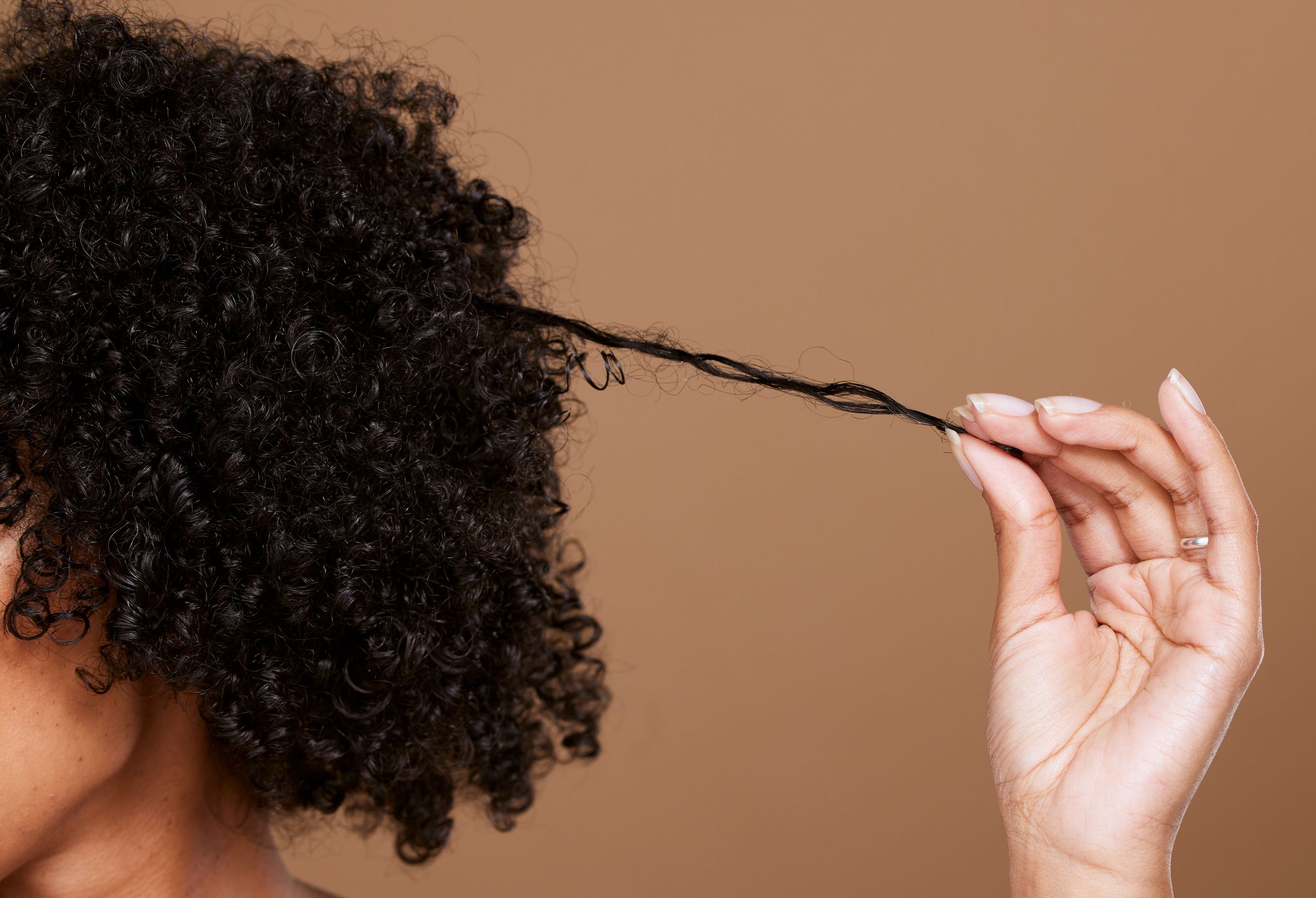 Mujer afro estira un mechón de pelo con su mano