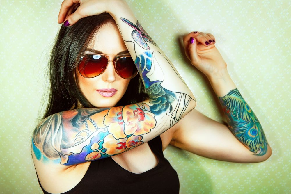 mujer con tatuajes de color en sus brazos