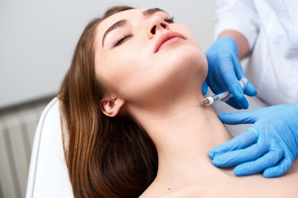 médico inyecta rellenos de ácido hialurónico en el cuello de una mujer joven