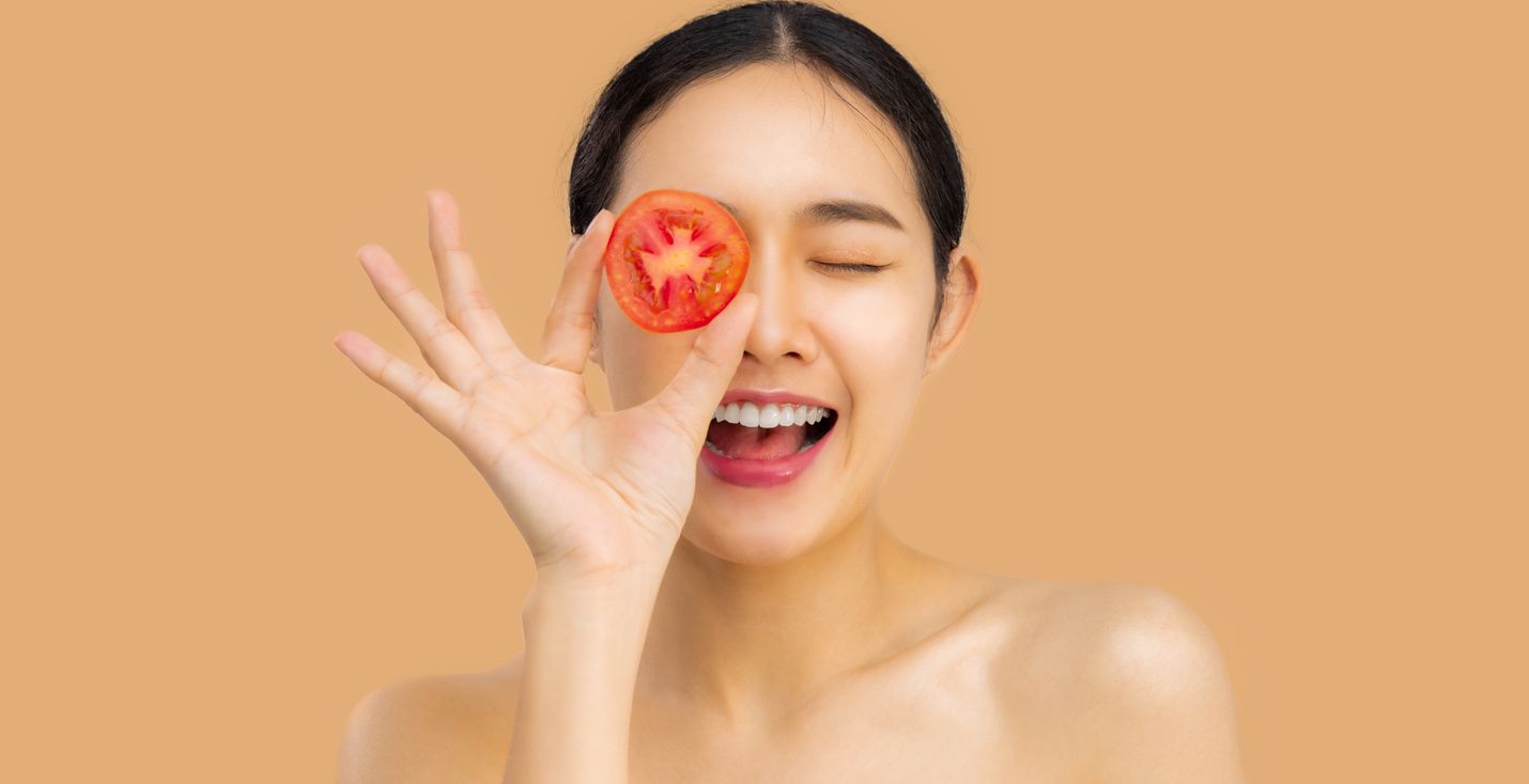 Mujer con rebanada de tomate en su cara
