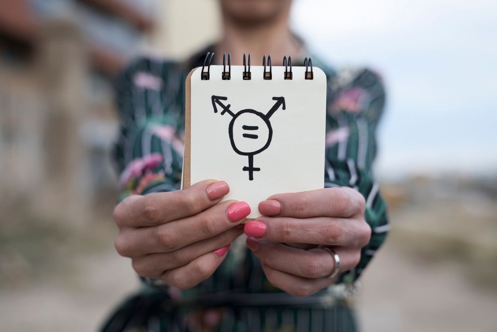 Mujer sostiene una libreta con el símbolo de transexualidad