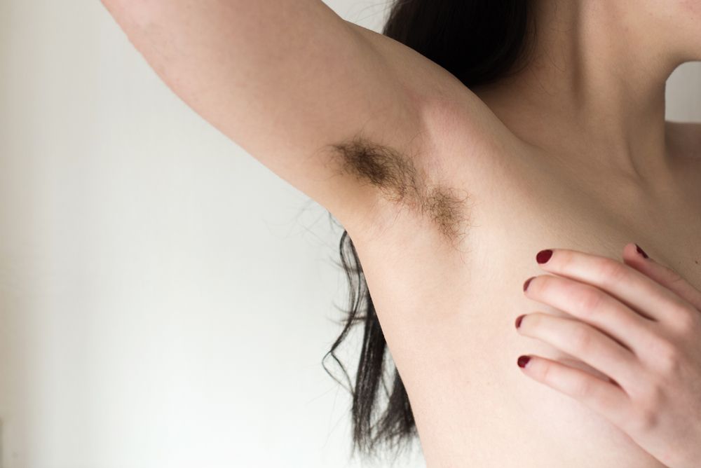 Una mujer levanta el brazo y muestra unas axilas sin afeitar