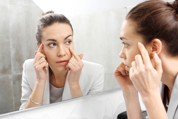 Mujer frente al espejo mirando la piel de su rostro